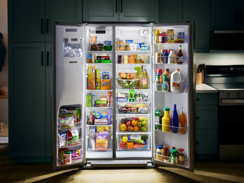 Open side-by-side refrigerator stocked with fresh and frozen foods Open side-by-side refrigerator stocked with fresh and frozen foods