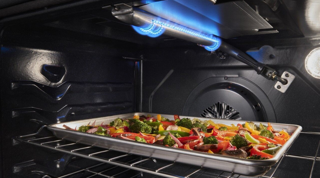 Sheet pan of roasted vegetables under a broiler element Sheet pan of roasted vegetables under a broiler element