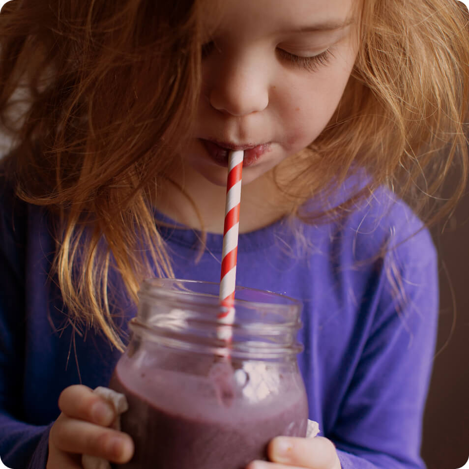 A child drinking a smoothie from a mason jar