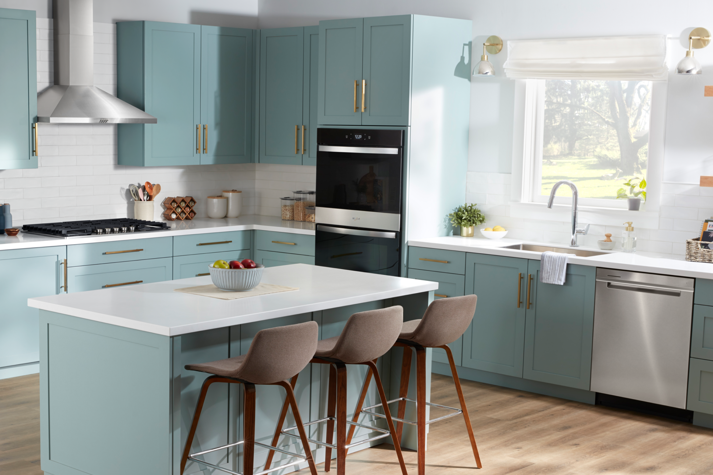 A bright kitchen with blue-green cabinets, a kitchen island and Whirlpool® Appliances
