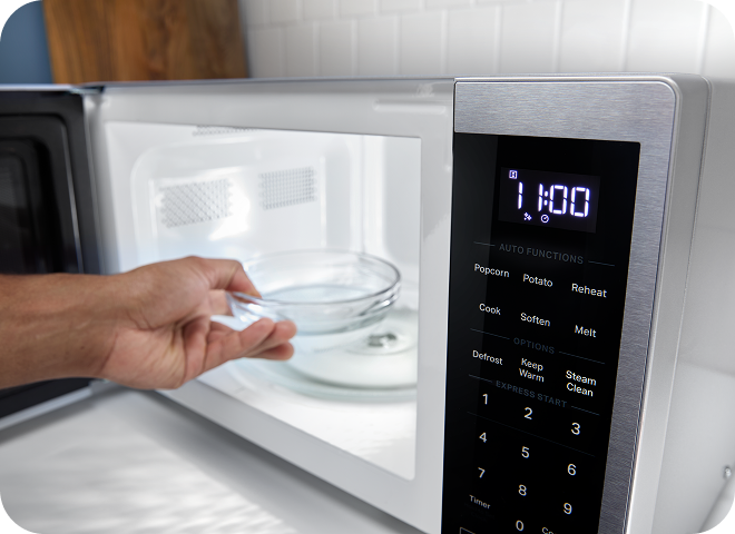 A person adding a bowl of water to a Whirlpool® Microwave