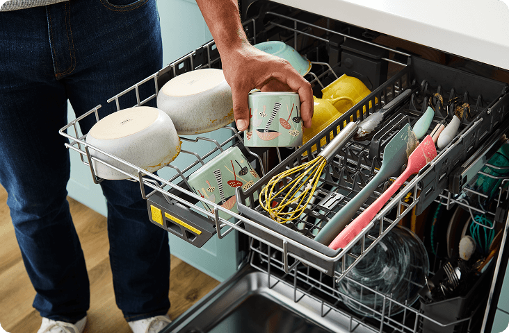 A third rack of a dishwasher loaded with clean bowls, cups and utensils
