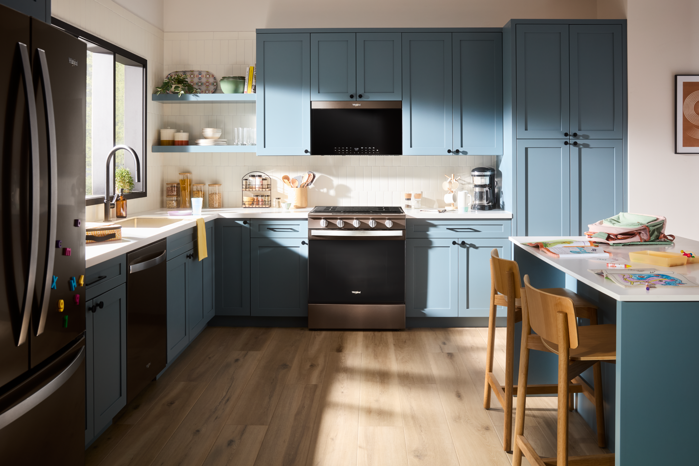 A kitchen with stainless steel Whirlpool® appliances and blue cabinets