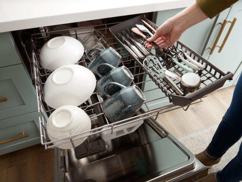 A person loading the third rack of a dishwasher A person loading the third rack of a dishwasher
