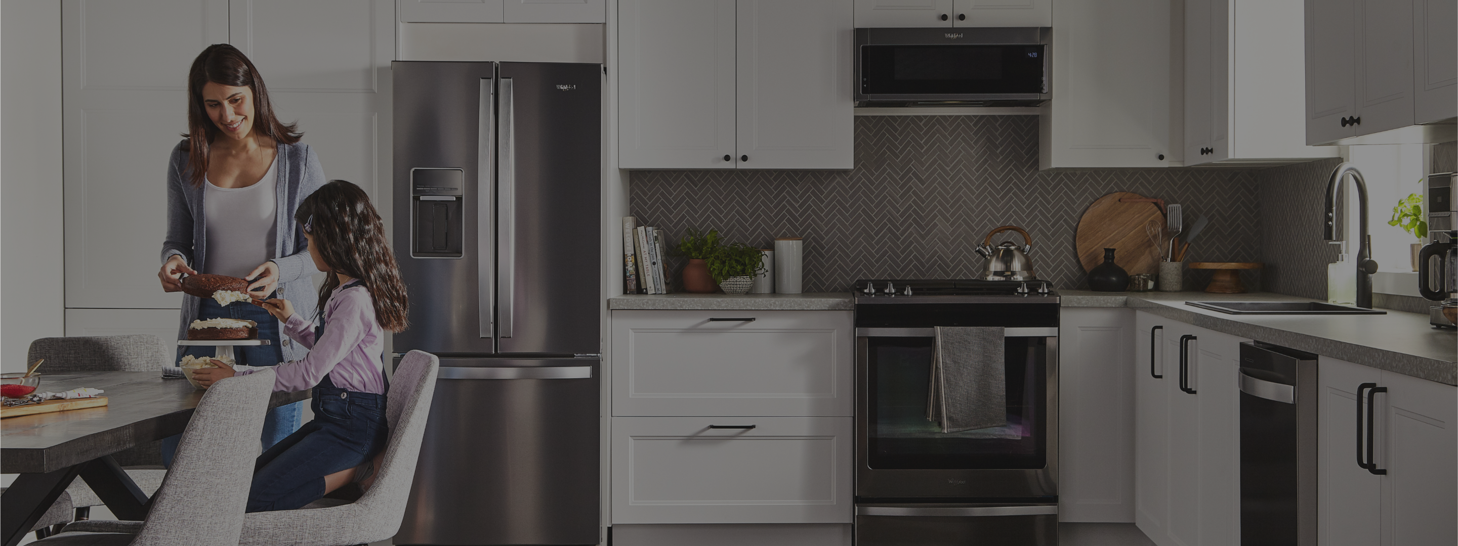 An adult and a child frosting a cake in a kitchen with Whirlpool® Appliances