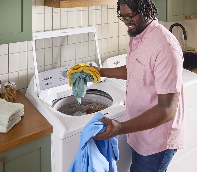 A person loading laundry into a Whirlpool® Washer