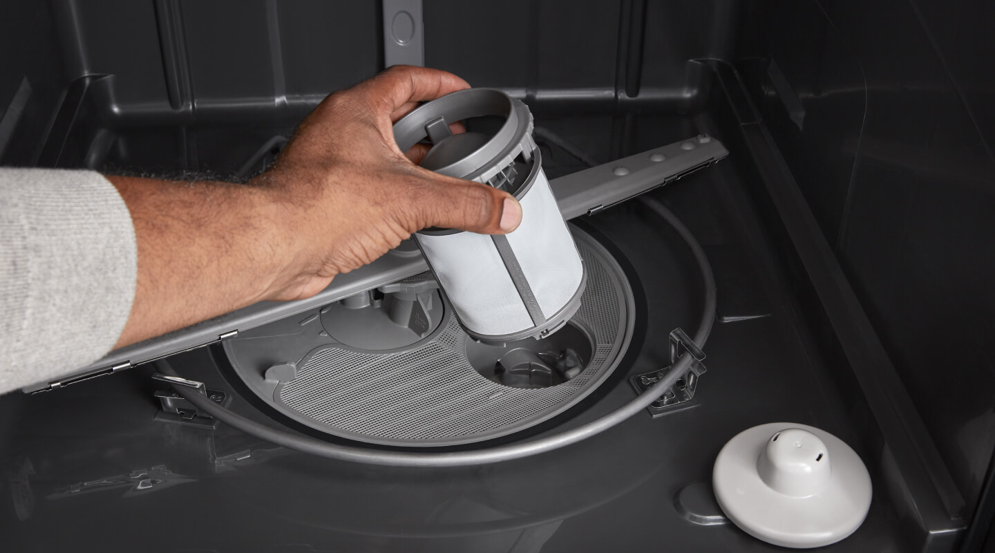 Person replacing dishwasher filter
