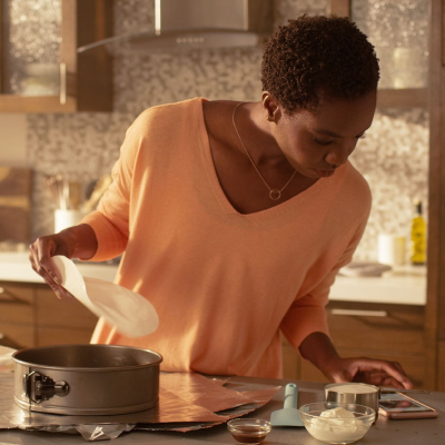 Person reviewing recipe on phone while preparing a springform pan