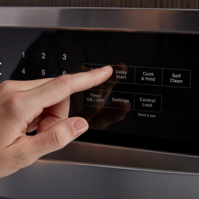 A person selecting the Delay Start option on an oven