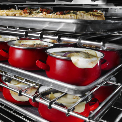 The inside of an oven with food cooking on all three racks