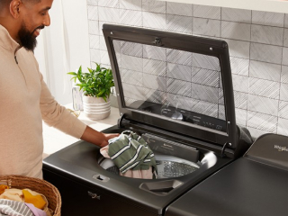 Person loading laundry in a top load washer