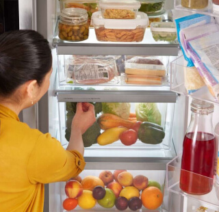 Person reaching inside a stocked refrigerator