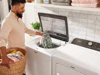 Person loading laundry in a top load washer
