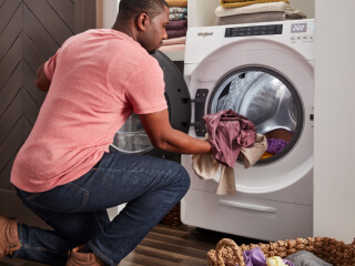 Person loading laundry in a front load dryer