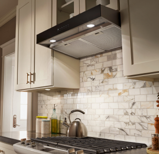 Gas cooktop and stainless steel range hood in white kitchen