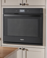 Black wall oven built into white cabinets