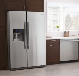 A Whirlpool® stainless steel refrigerator surrounded by brown cabinetry