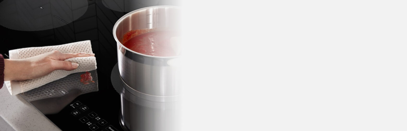 Person wiping a spill on a glass cooktop