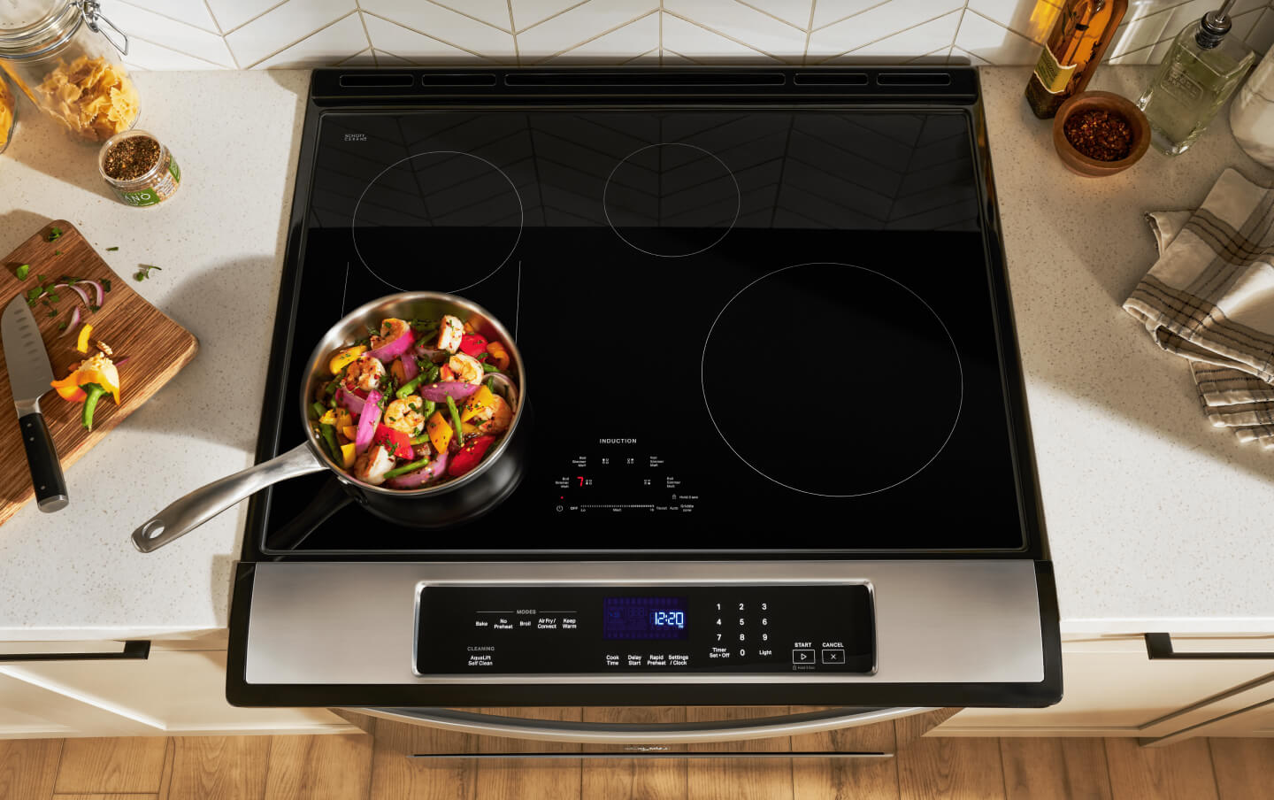 An overhead image of an induction cooktop that has a pan of vegetables on one of the front burners