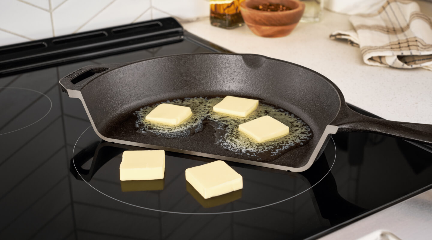 Photo of half a pan on a stove with butter melting on it, and next to it, non-melting pads of butter on the cooktop