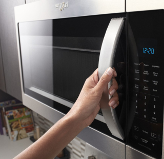 A person opening a microwave door