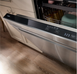 An open stainless steel Whirlpool® Dishwasher with dishes inside