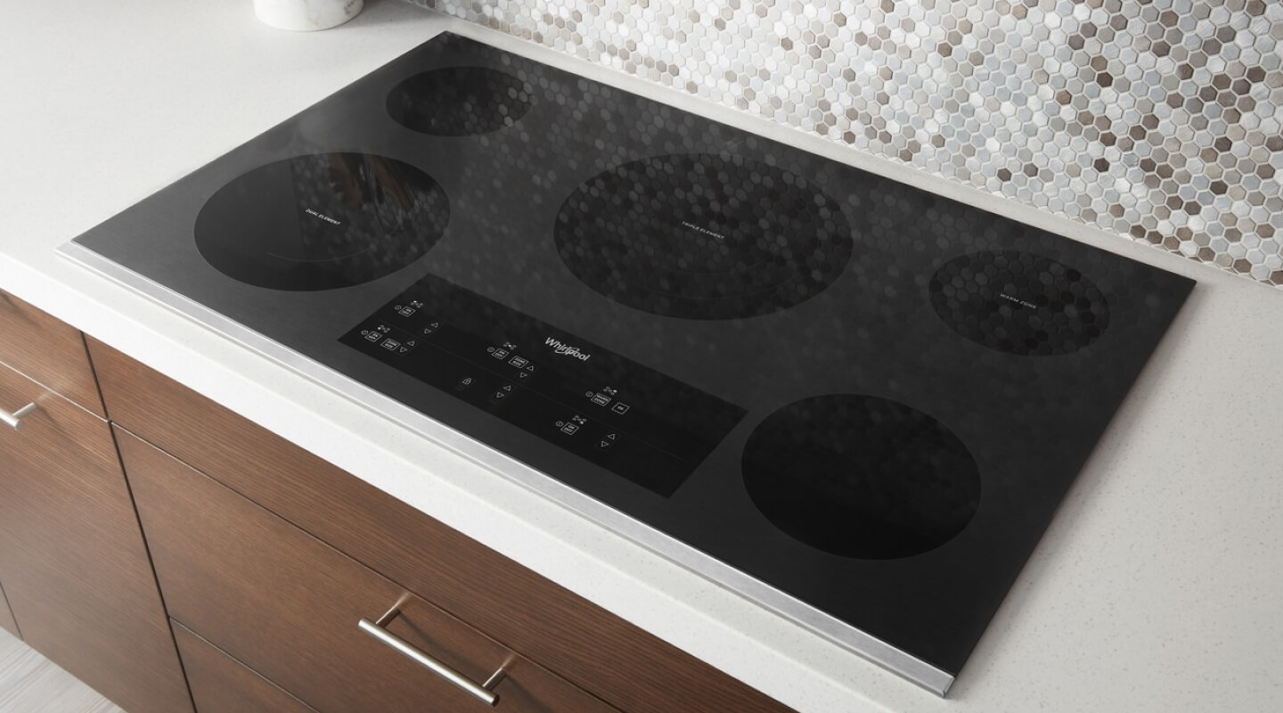 Electric cooktop installed on white countertop in brown cabinetry