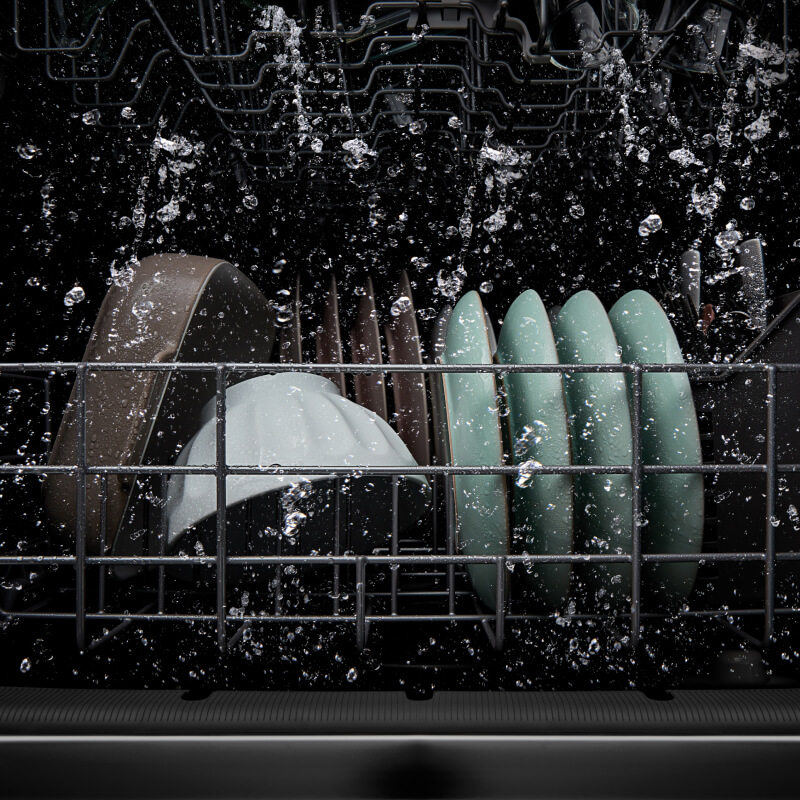 Bottom rack of a loaded dishwasher with water spraying around