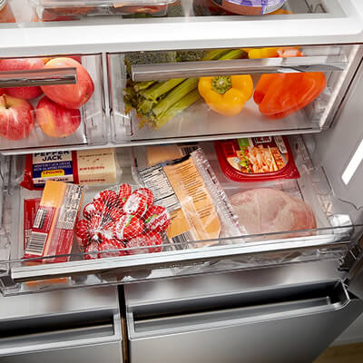 Pull-out drawer stocked with small snack items below humidity crispers