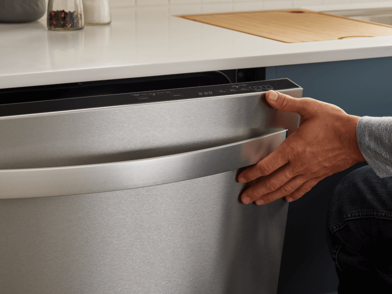 Person closing a top control dishwasher