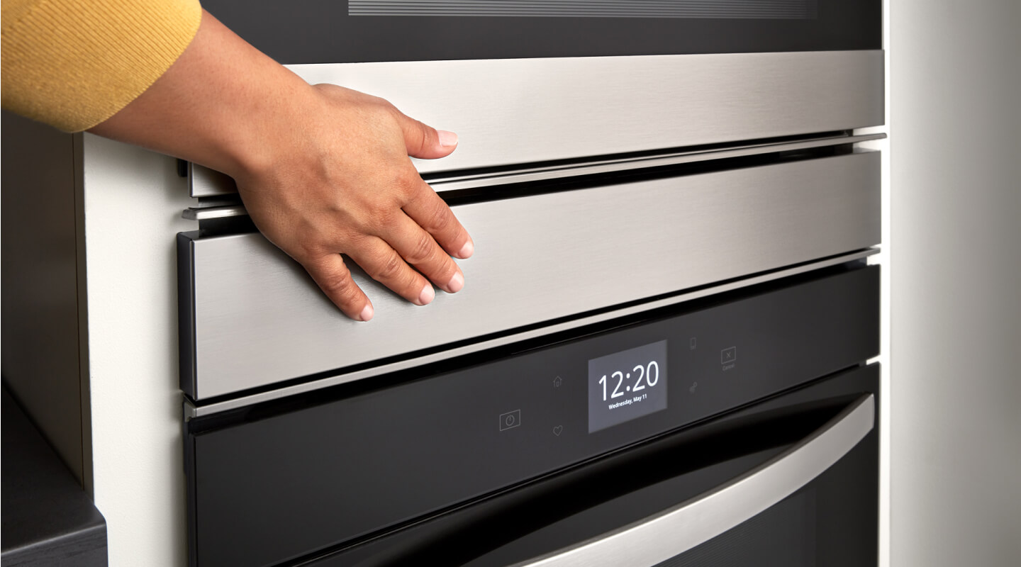 Hand closing a stainless steel wall oven