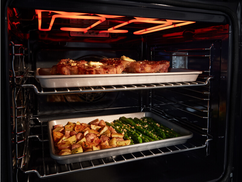 Pans of food cooking inside oven Pans of food cooking inside oven