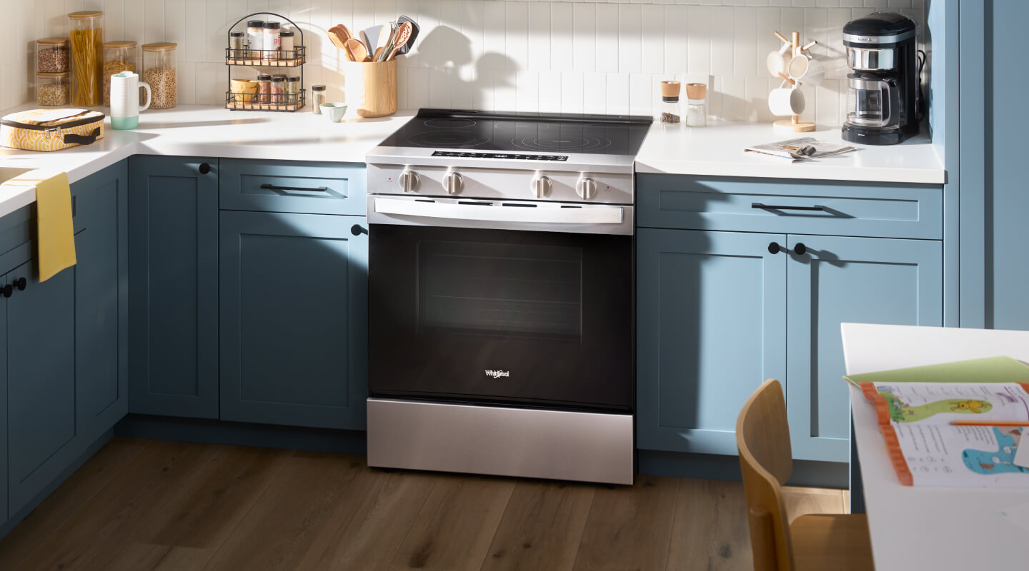 The interior of a kitchen with blue cabinetry and an electric range