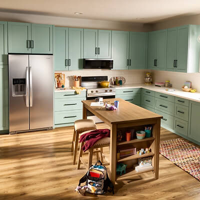 A kitchen with teal cabinets and Whirlpool® appliances