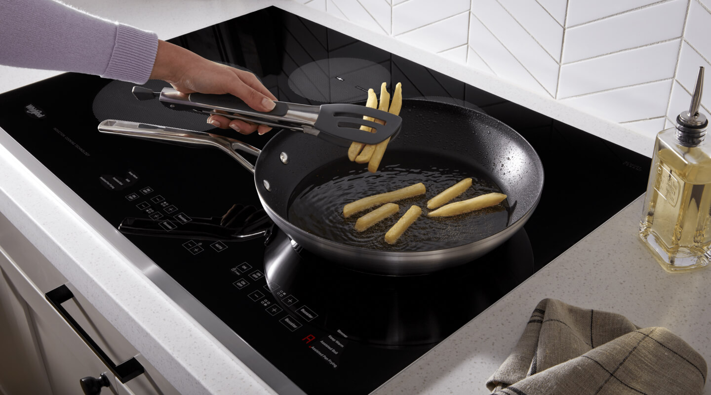 A person cooking French fries on an induction cooktop
