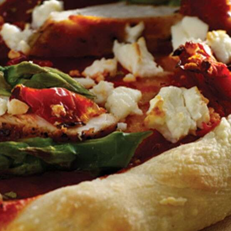 Close-up of pizza with cheese crumbles and greens on top