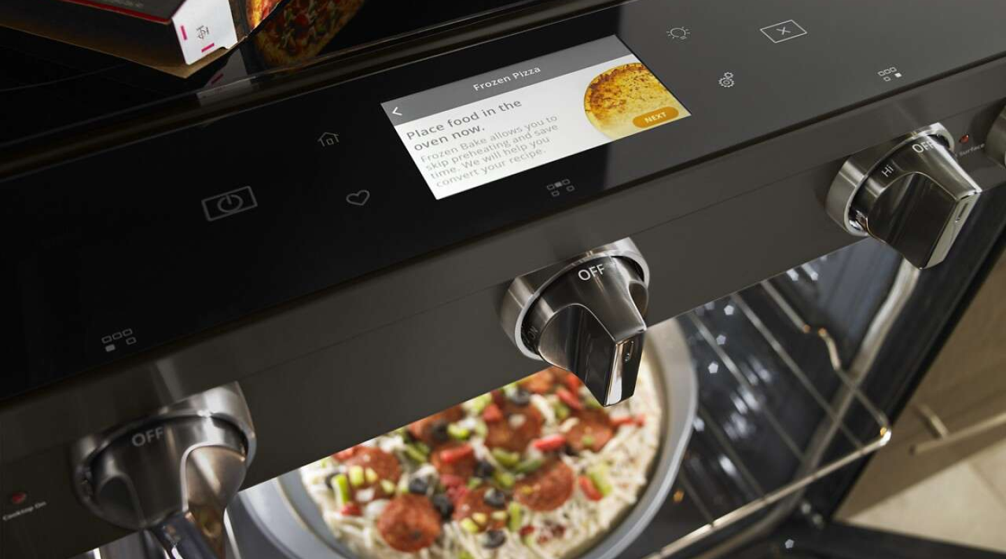 Birds-eye view of frozen pizza in the oven and the oven control panel with pizza cooking instructions