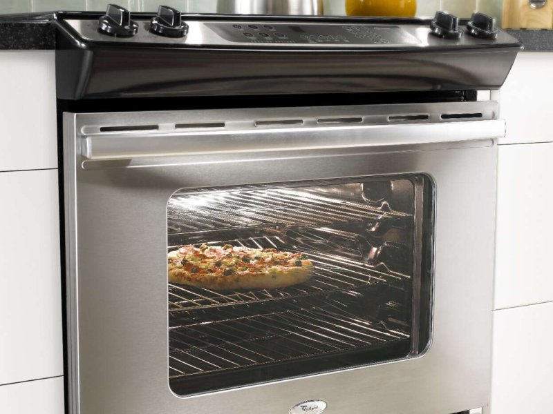 Pizza cooking inside of an oven with the oven light on