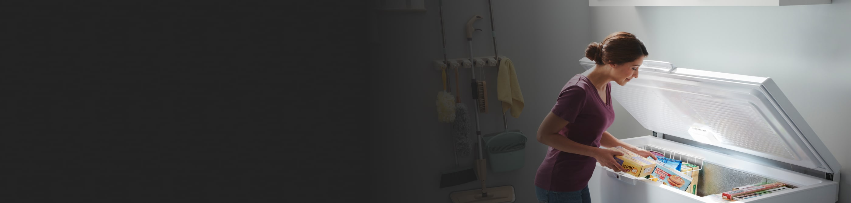 Person loading frozen food into a white chest freezer