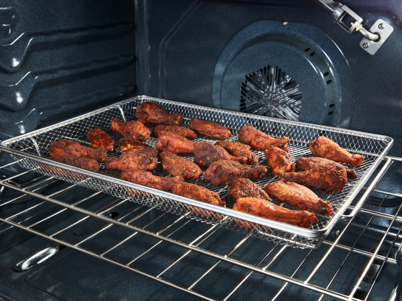 Chicken wings in an air fryer basket Chicken wings in an air fryer basket