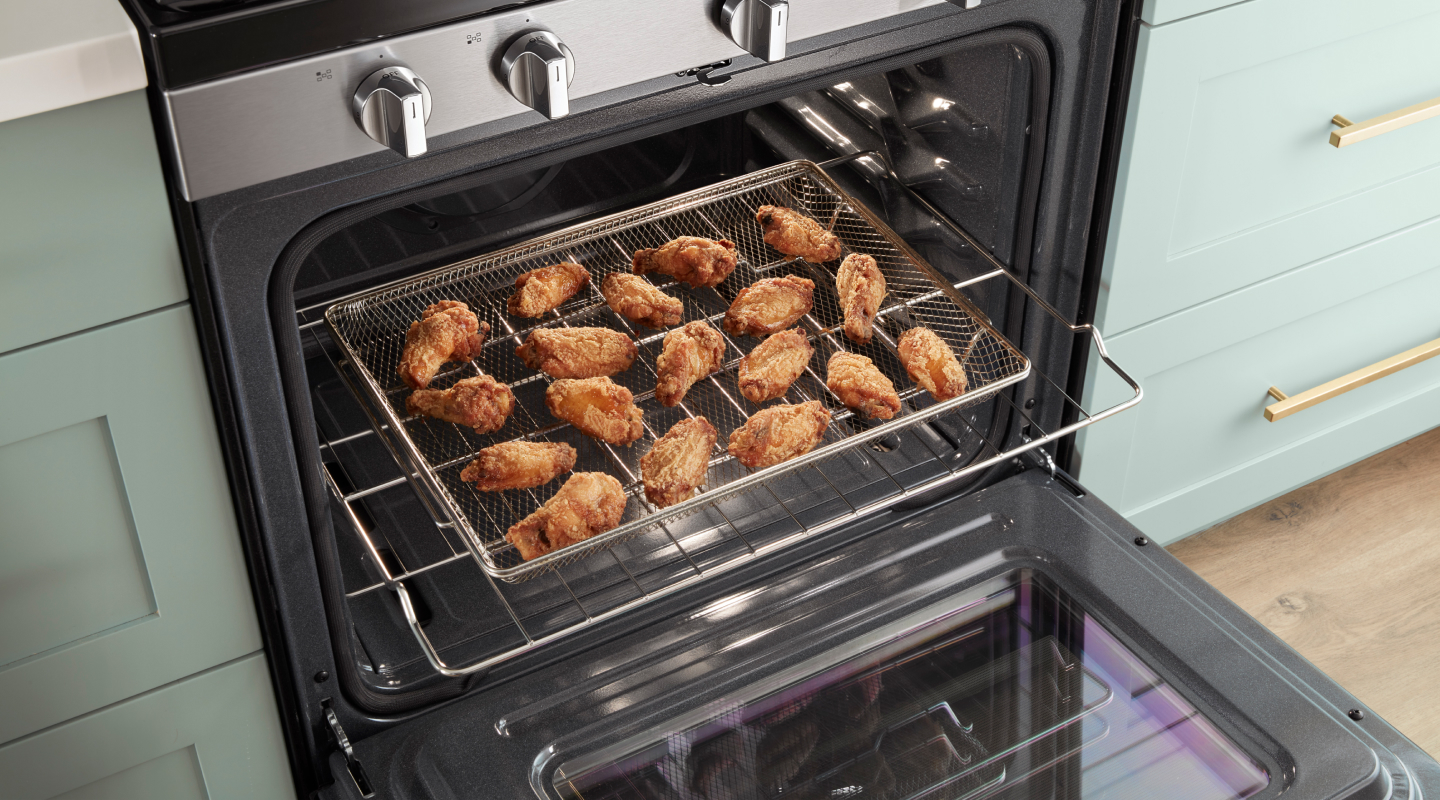 Chicken in an air fryer basket on an oven rack