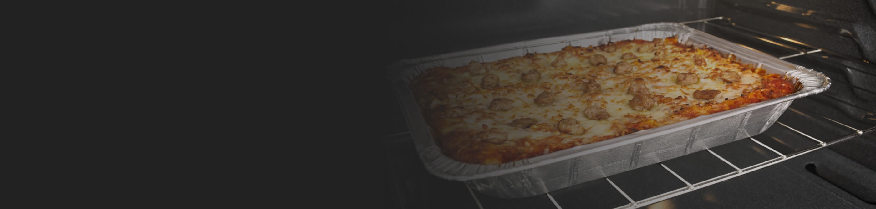 Lasagna cooking in a foil pan in the oven