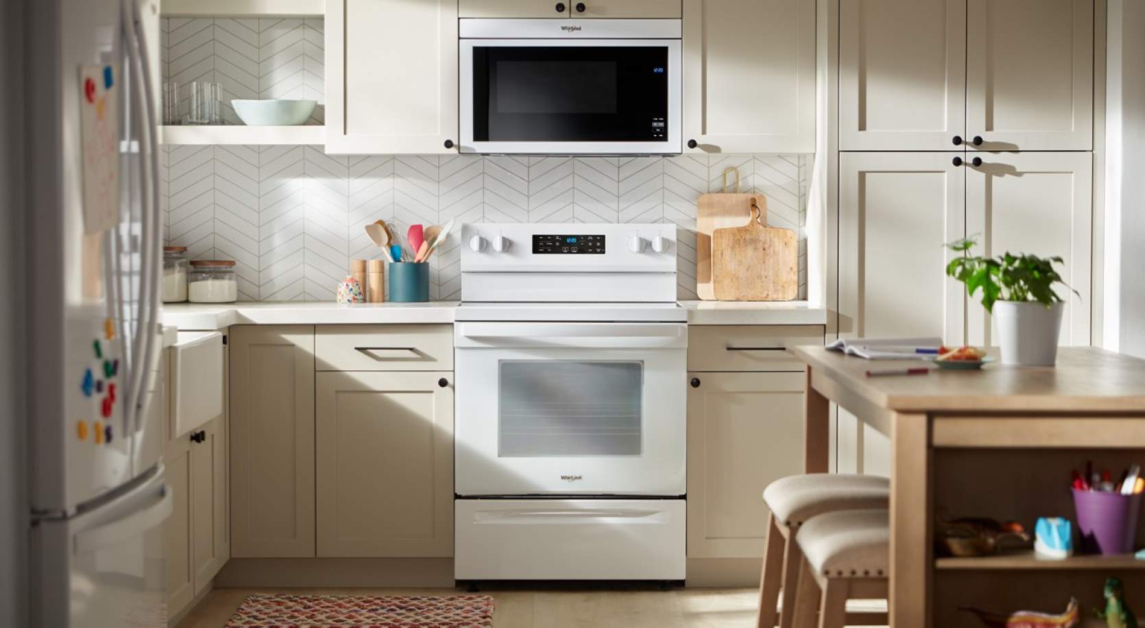 A white range and over-the-range microwave in a kitchen with cream cabinetry and white backsplash