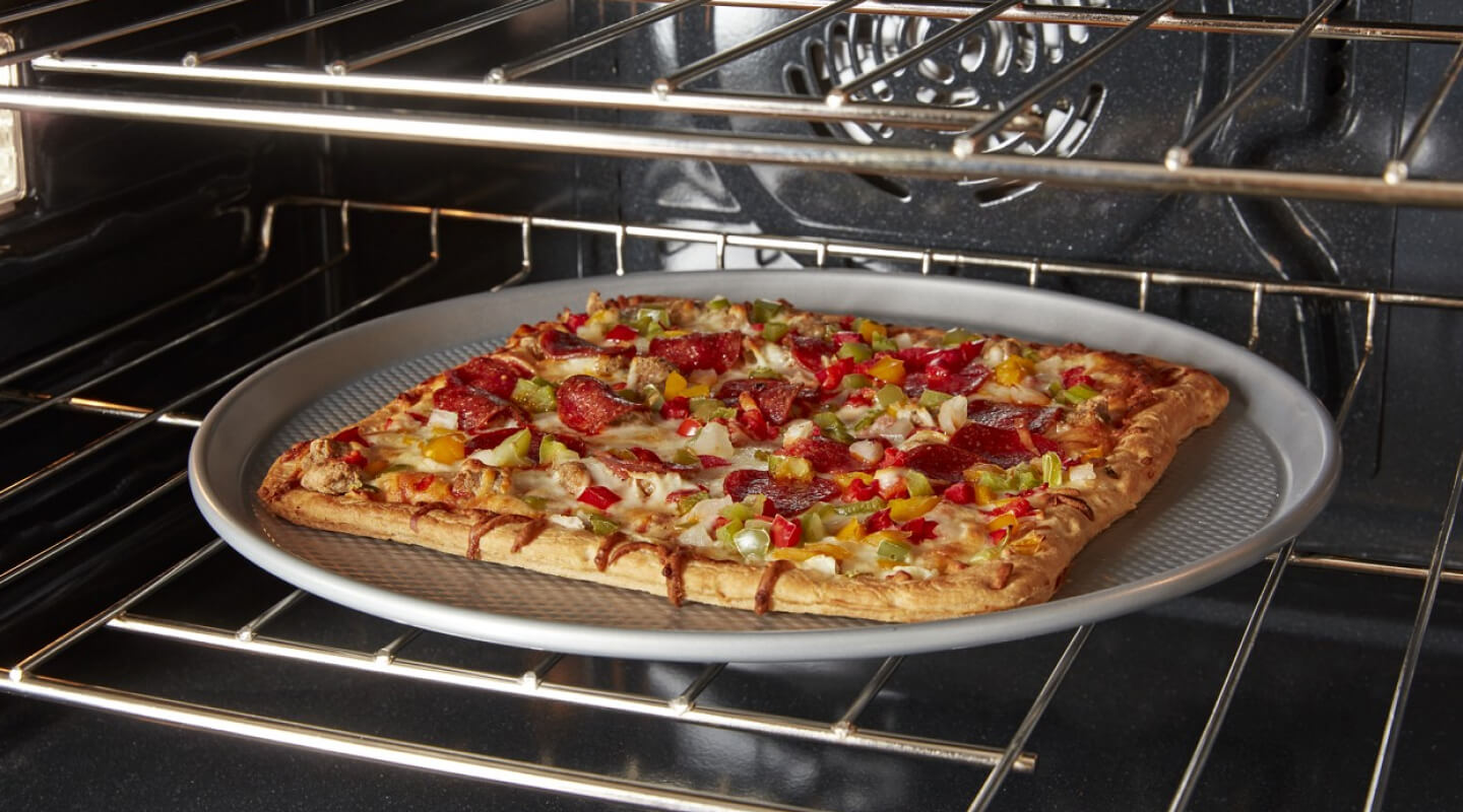A square pizza cooking in a convection oven