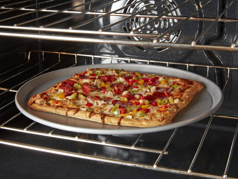 A square pizza cooking in a convection oven