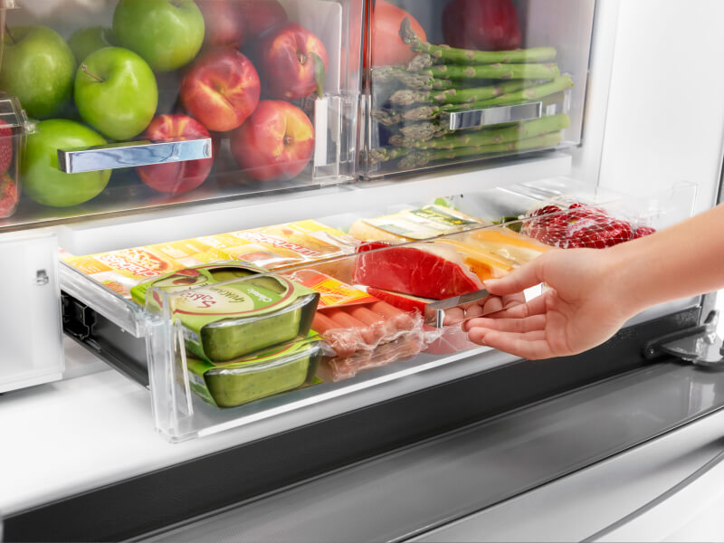 A person pulling out a fridge drawer A person pulling out a fridge drawer