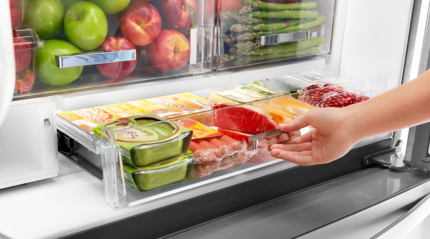 A person pulling out a fridge drawer A person pulling out a fridge drawer