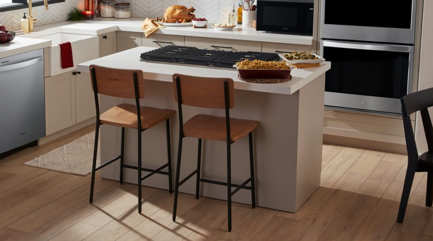 Two counter stools at a kitchen island with a built-in gas cooktop