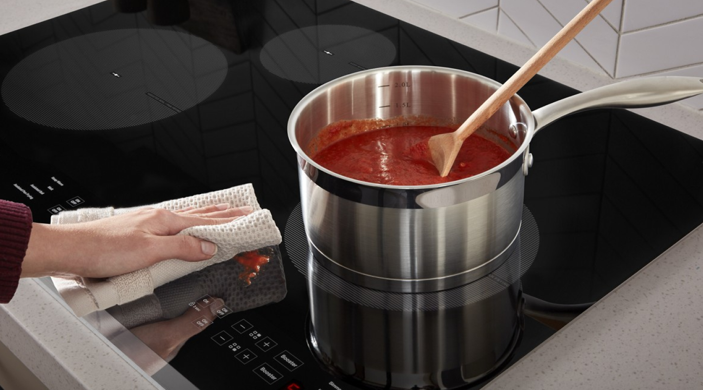 Hand wiping down a sauce spill with a rag 