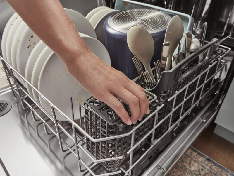 Hand reaching into a full dishwasher